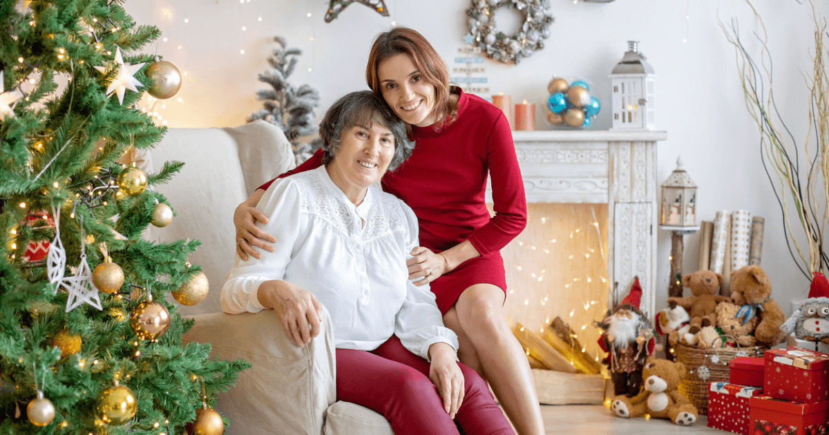 Senior mom with adult daughter by the Christmas tree for the holidays