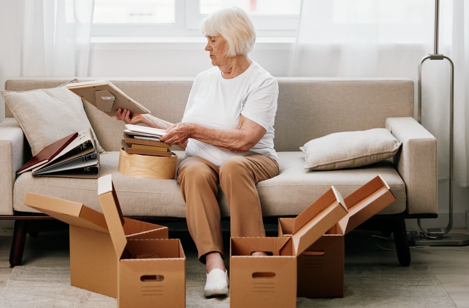 A senior sorts through photo albums and picture frames to decide which to pack for a move to memory care