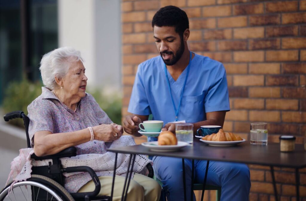  A nurse passes a senior a cup of coffee during a breakfast together at a senior living community