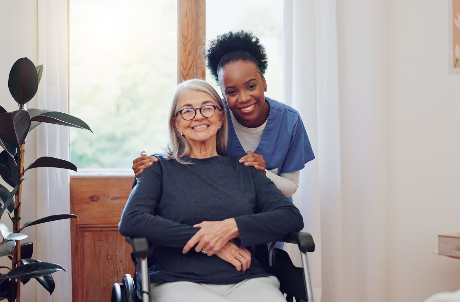 caregiver holding a senior with wheelchair and smiling together